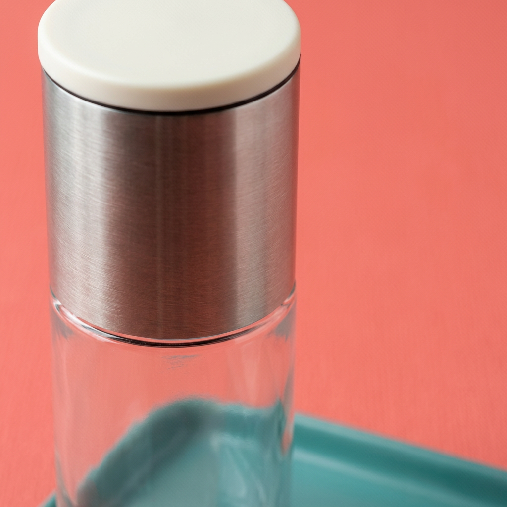 Concept close-up of ivory cap, brushed silver-tone housing and transparent reservoir